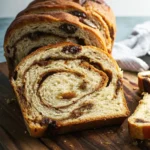 a loaf of Vegan Cinnamon Swirl Bread with raisins on a wooden surface