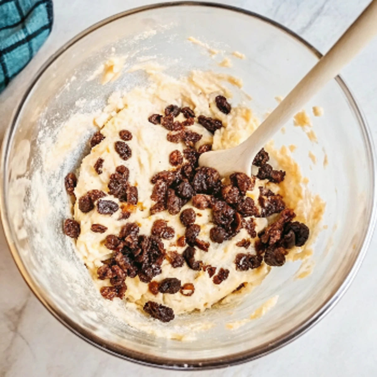 a bowl of dough with raisins and a wooden spoon for Cinnamon Raisin Bread Recipe